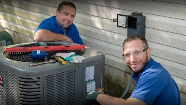 Two HVAC technicians working to repair an AC unit.